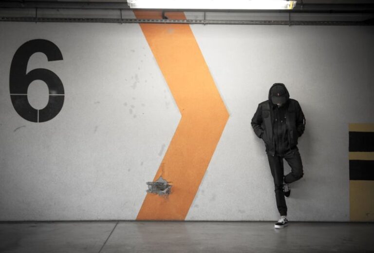 Urban - man leaning on white wall of the parking area