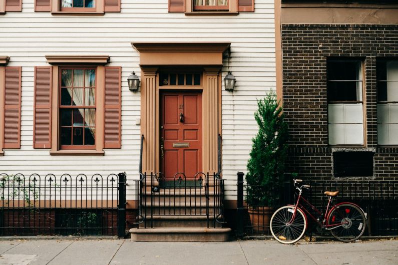 Urban House - red bicycle parked beside black metal gate in front house