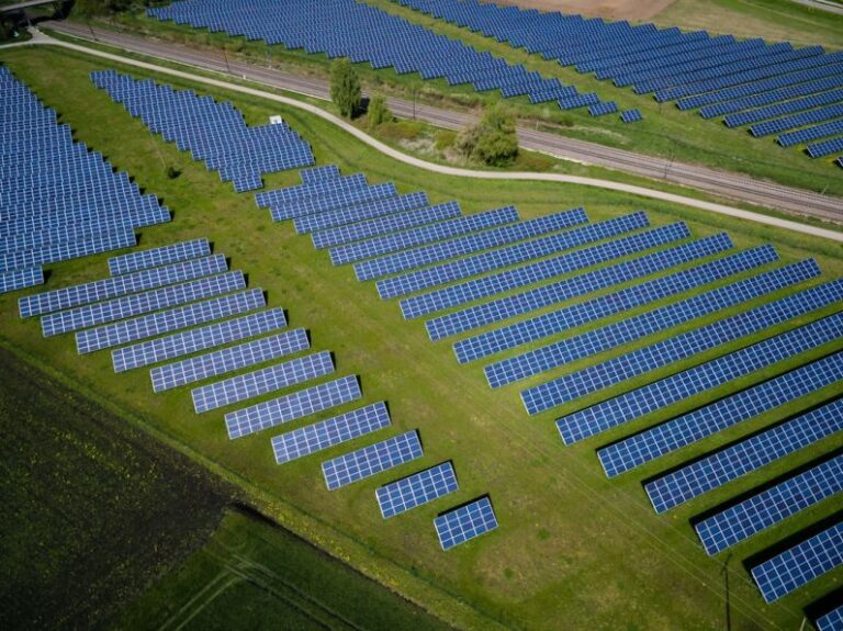 Renewable Energy - aerial photography of grass field with blue solar panels