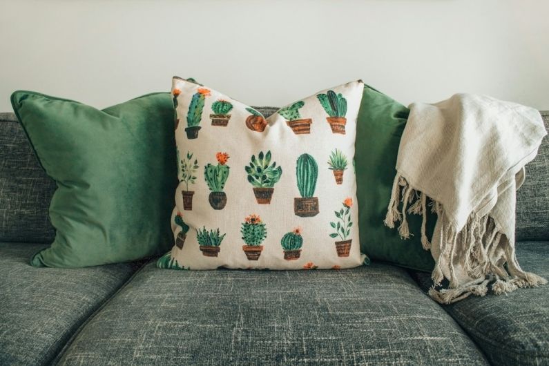 Interiors Textile - three throw pillows and one white fringed blanket placed on top of gray sofa